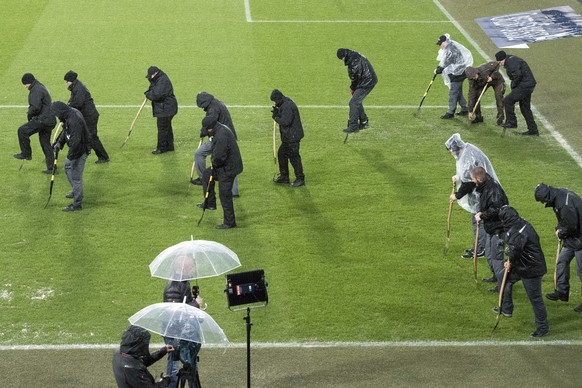 Staff members work under heavy rain to evacuate water from the field, prior the 2018 Fifa World Cup play-offs second leg soccer match Switzerland against Northern Ireland at the St. Jakob-Park stadium ...