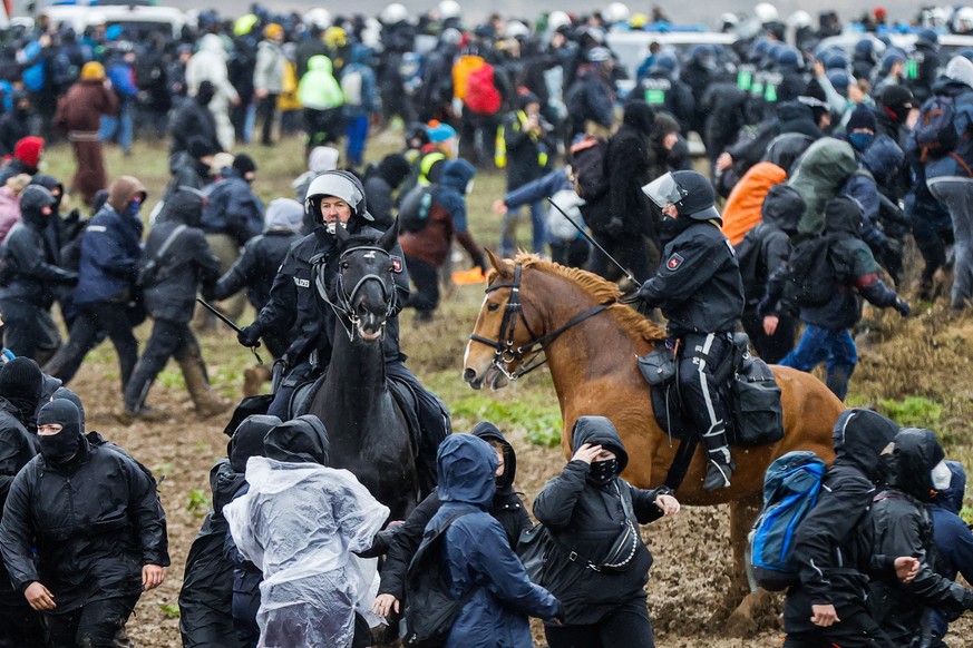 epa10405031 Police officers on horses ride between protesters during a rally of climate protection activists near the village of Luetzerath, Germany, 14 January 2023. Luetzerath in North Rhine-Westpha ...