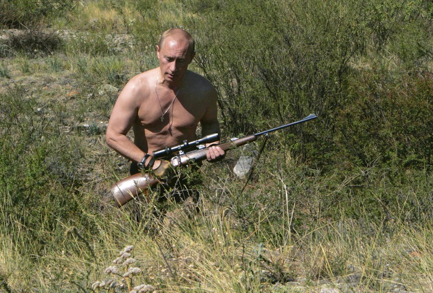 Russian President Vladimir Putin walks holding a rifle in the Tuva region of Siberia in this Wednesday, Aug. 15, 2007 photo. He rides horses. He fishes half-naked in icy rivers. He's a 54-year-old, wi ...