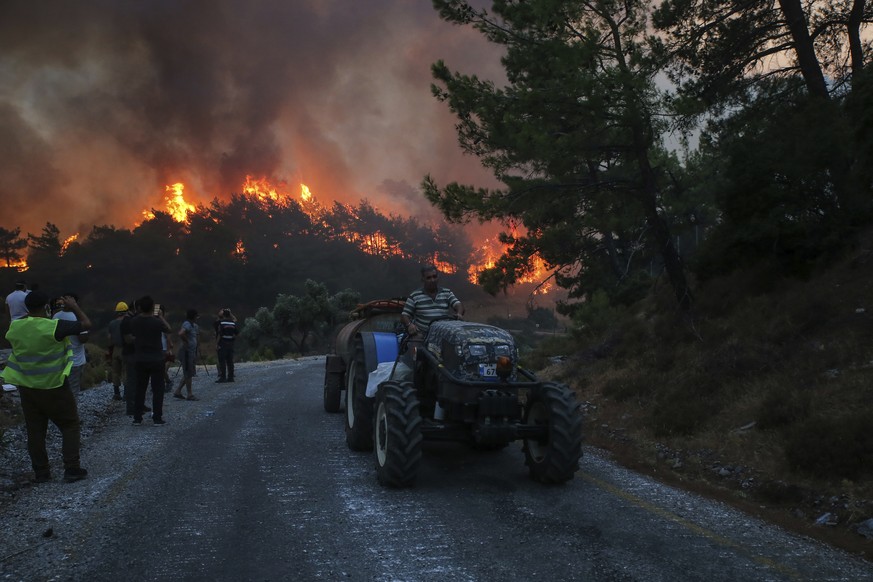 People watch a wildfire near Akcayaka village in Milas, Mugla in southwest Turkey, Thursday, Aug. 5, 2021. A wildfire that reached the compound of a coal-fueled power plant in southwest Turkey and for ...