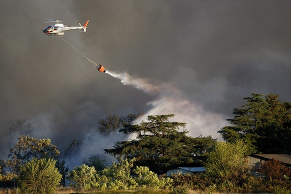 An helicopter drops water on a fire that broke out in Rome, Saturday, July 9, 2022. (Roberto Monaldo/LaPresse via AP)