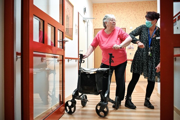 epa08419273 A nurse and an elderly woman show how to greet at the retirement home &#039;Zur Heiligen Familie&#039; in Duesseldorf, Germany, 13 May 2020. After six weeks of isolation, residents of old  ...