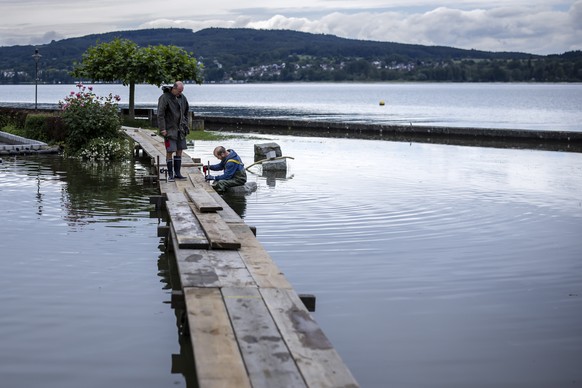 A municipal employee and and a volunteer build footbridges as the Lake Untersee, the western part of Lake Bodensee overflows its banks, in Berlingen, Switzerland, Tuesday, June 11, 2024. On Tuesday, t ...