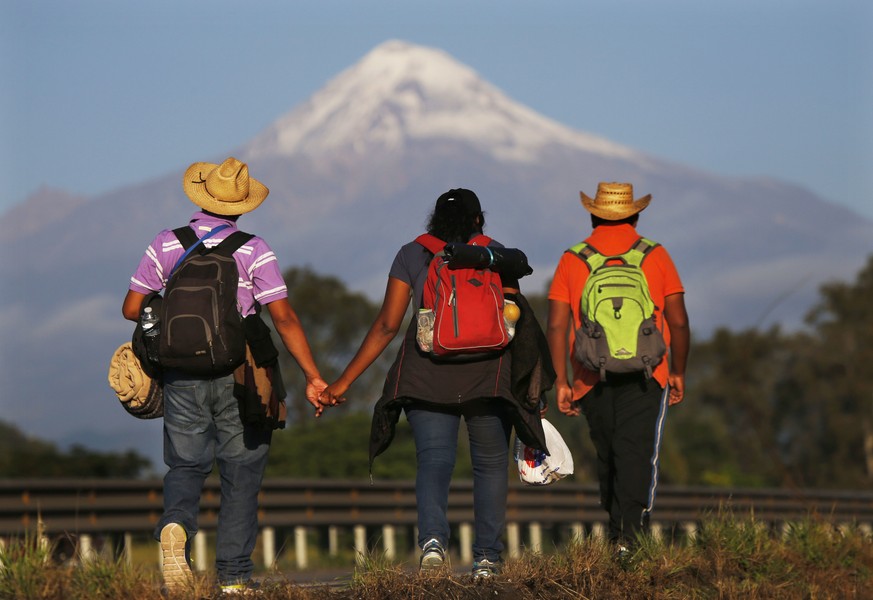 In this Nov. 5, 2018 photo, Central American migrants begin their morning trek facing Pico de Orizaba volcano as part of a thousands-strong caravan hoping to reach the U.S. border, upon departure from ...
