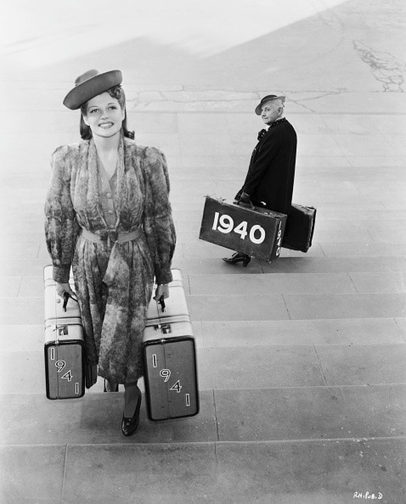1941: A young Rita Hayworth (1918 - 1987) sees in the New Year with a pair of &#039;1941&#039; suitcases as she passes writer Quentin Crisp carrying a pair of &#039;1940&#039; suitcases on the way out ...