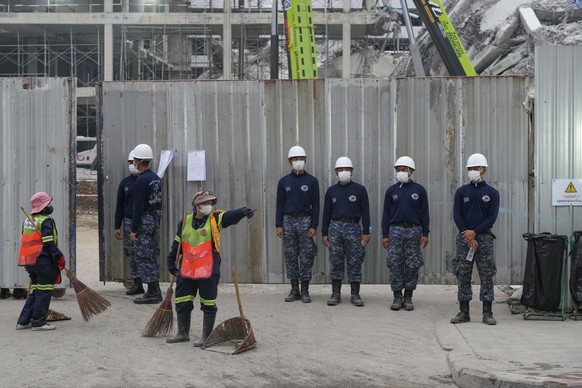 Thai army soldiers stand guard as municipal workers clean the area outside the site of an under-construction high-rise building that collapsed after an earthquake in Bangkok, Thailand, Monday, March 3 ...