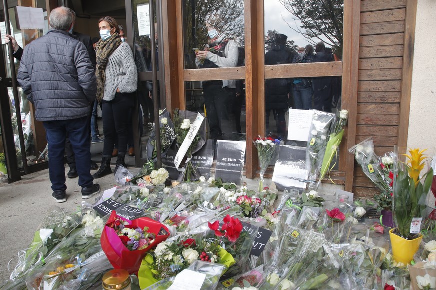 Flowers lay outside the school where slain history teacher Samuel Paty was working, Saturday, Oct. 17, 2020 in Conflans-Sainte-Honorine, northwest of Paris. French President Emmanuel Macron denounced  ...
