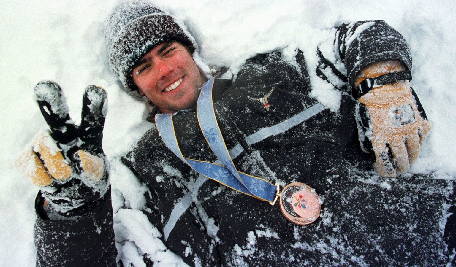 Der Schweizer Snowboarder Ueli Kestenholz waelzt sich am Montag, 9. Februar 1998, im Schnee von Shiga Kogen, geschmueckt mit der Bronzemedaille, die er am Vortag am olympischen Snowboard- Riesenslalom ...