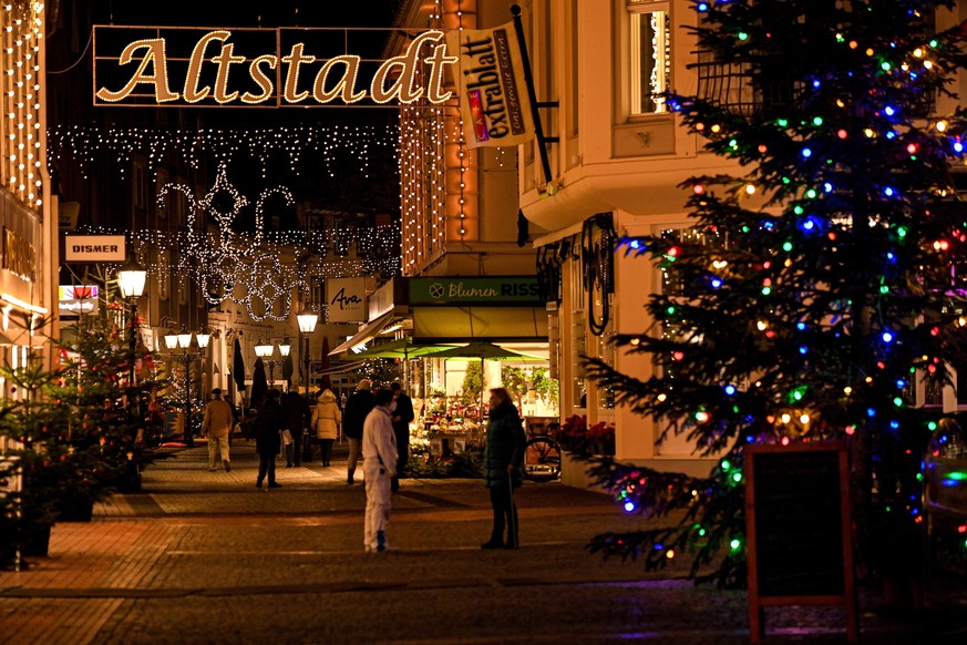 epa08870830 Pedestrians walk past stores in Christmassy decorated alleys in the city centre of Moers, Germany, 08 December 2020. Throughout Germany, numerous restrictions have been in place in the fig ...