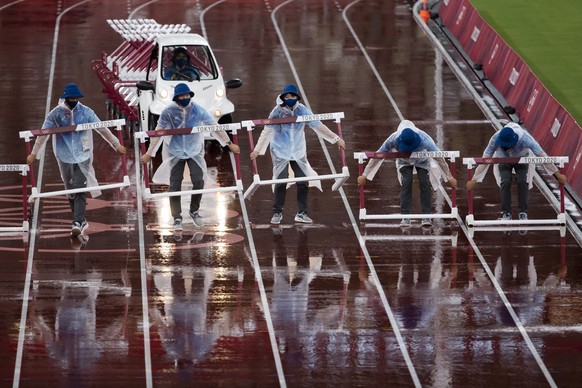 epa09388398 Volunteers remove the hurdles after the women&#039;s 400m Hurdles semi finals during the Athletics events of the Tokyo 2020 Olympic Games at the Olympic Stadium in Tokyo, Japan, 02 August  ...