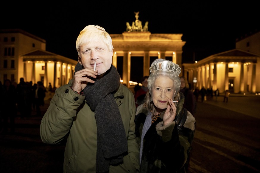 Two participants in a flash mob wearing masks of British Prime Minister Boris Johnson and Queen Elizabeth II stand in front of the Brandenburg Gate in Berlin Friday, Jan. 31, 2020 to mark Britain&#039 ...