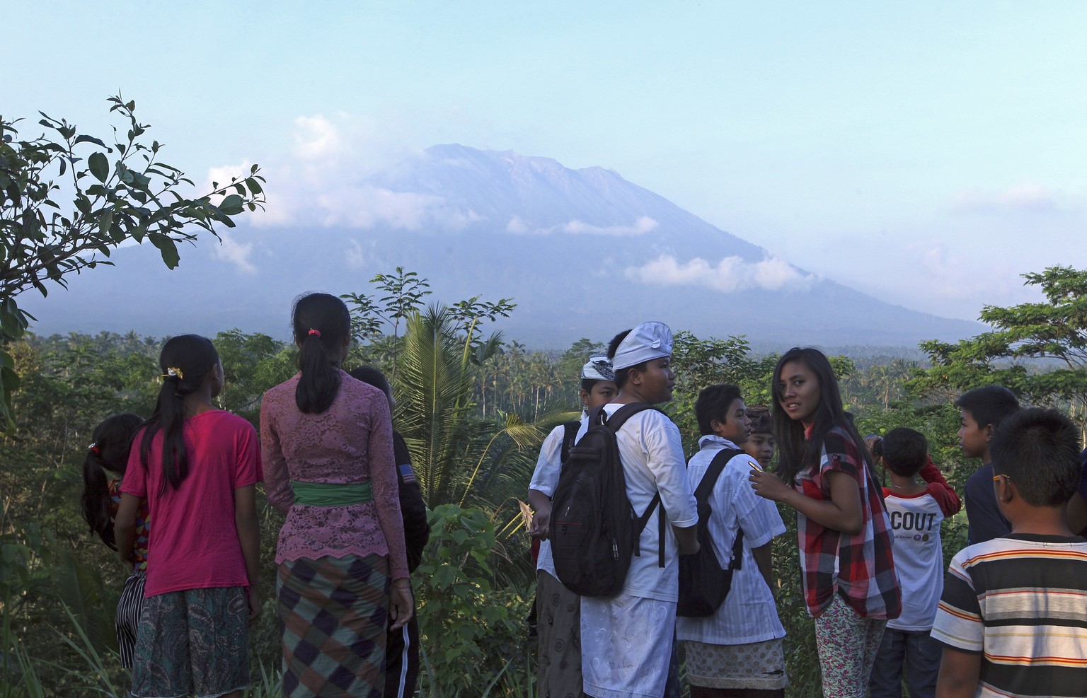 Residents observe the Mount Agung from a viewing point in Bali, Indonesia, Wednesday, Sept. 20, 2017. Officials have more than doubled the size of the evacuation zone around the Mount Agung volcano on ...