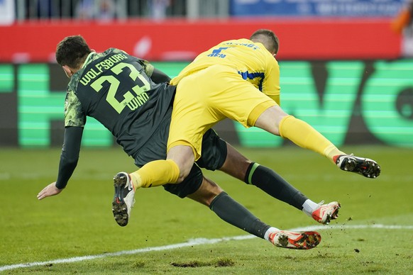 16.12.2023, Hessen, Darmstadt: Fu�ball: Bundesliga, SV Darmstadt 98 - VfL Wolfsburg, 15. Spieltag, Merck-Stadion am B�llenfalltor. Wolfsburgs Jonas Wind (l) und Darmstadts Torwart Marcel Schuhen sto�e ...