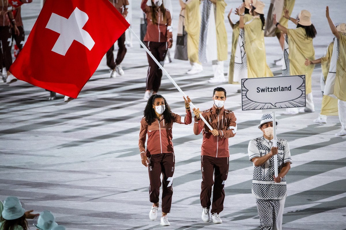 Switzerland's flag-bearers sprinter Mujinga Kambundji and epee fencer Max Heinzer celebrate during the opening ceremony of the 2020 Tokyo Summer Olympics at the National Stadium in Tokyo, Japan,  ...