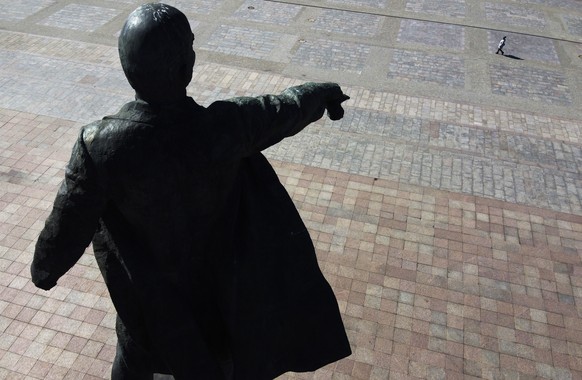 A woman walks past a statue of Soviet Union founder Vladimir Lenin, in a nearly-empty square due to residents staying at home to avoid the spread of the coronavirus, in St. Petersburg, Russia, Wednesd ...