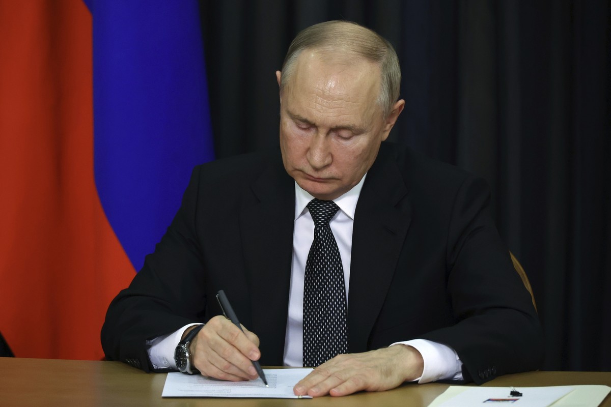 Russian President Vladimir Putin writes down notes as he attends a plenary session of the World Russian People's Council, dedicated to the 30th anniversary of the founding of the organisation, vi ...