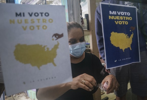 Salon owner Alejandra Moran tapes flyers to a door as part of a campaign to get voters to the polls by La Colmena, a community-based organization working with immigrant workers, in the largely Hispani ...