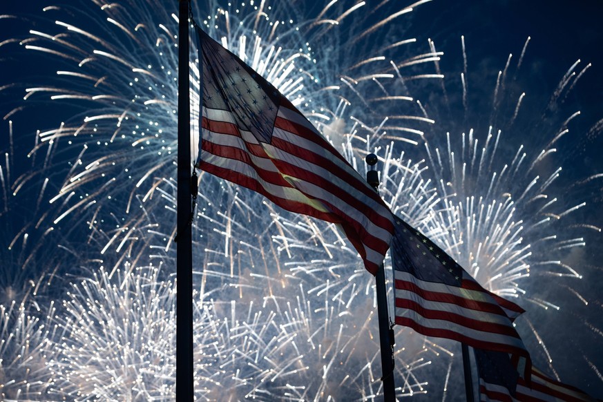 U.S. Army 250th anniversary / Trump birthday parade Fireworks explode behind American flags at the Washington Moument at the conclusion of a military parade celebrating the U.S. Armys 250th anniversar ...