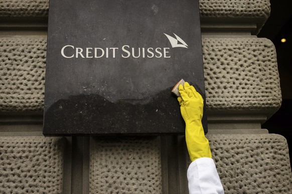An activist of Scientist Rebellion symbolically cleans the entrance of the Swiss Bank Credit Suisse at Paradeplatz during a protest against fossil fuel investments, in Zurich, Switzerland, on Wednesda ...