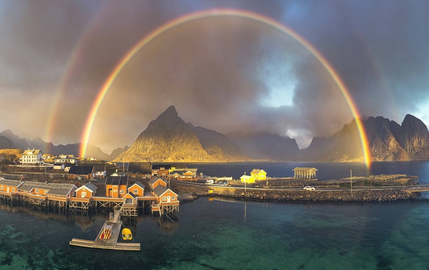 Aerial view of idyllic rainbows over Olstind mountain and fishermen cabins by the sea, Sakrisoy, Reine, Lofoten Islands, Nordland, Norway, Scandinavia, Europe Copyright: RobertoxMoiola 1179-6327 RECOR ...