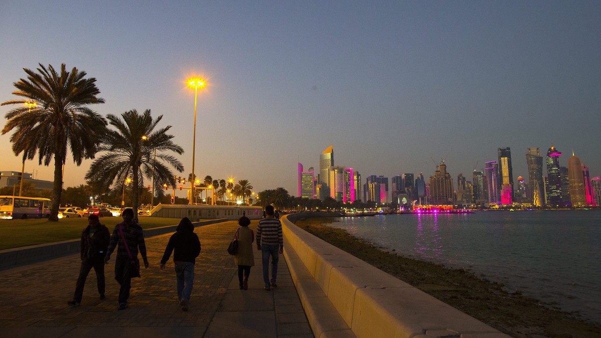 epa04591688 People walk on the corniche promenade in front of the skyline of Doha's West Bay high rise buildings at sunset, Doha, Qatar, 28 January 2015. The men's Handball World Championshi ...