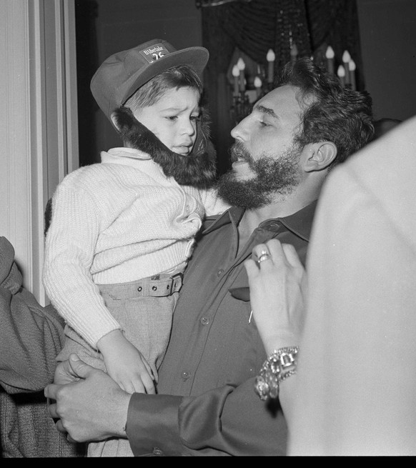 Cuban Prime Minister Fidel Castro holds a four-year-old boy, Carlos Sarzo, outfitted in fatigues and Castro-style beard, during a reception at the Cuban Embassy in Washington, April 17, 1959. (AP Phot ...