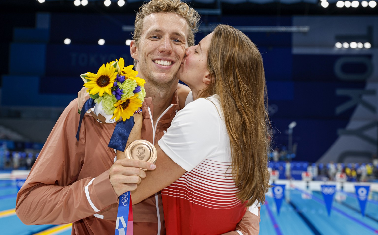 epa09378521 Jeremy Desplanches of Switzerland is being kissed by his girlfriend Charlotte Bonnet of France while posing for a photo with his Bronze medal after finishing third in the men&#039;s 200m I ...