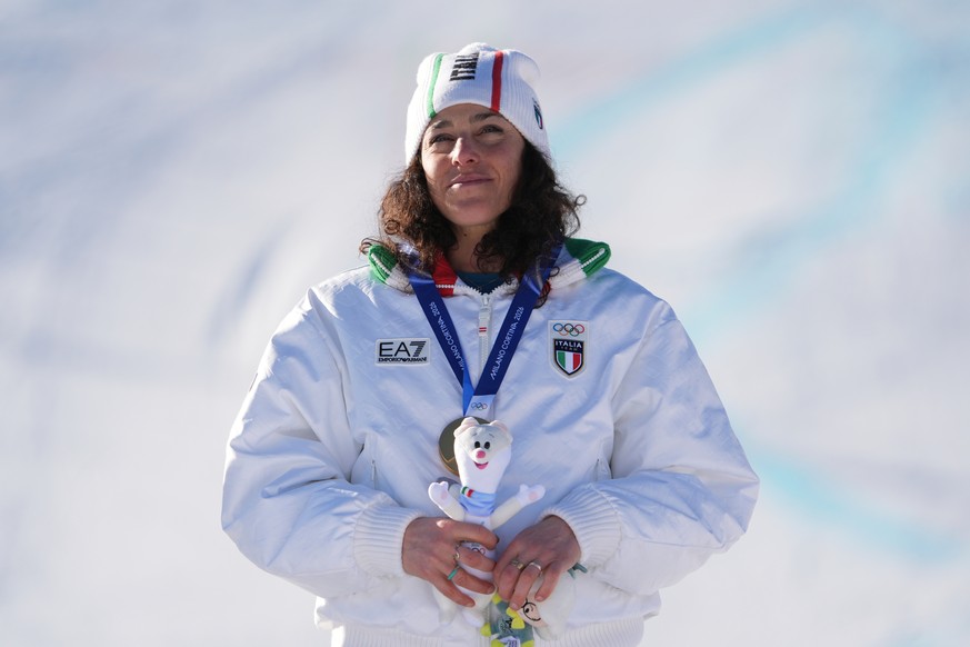 Italy's Federica Brignone listens to the national anthem as she wears the gold medal in an alpine ski, women's giant slalom race, at the 2026 Winter Olympics, in Cortina d'Ampezzo, Ital ...