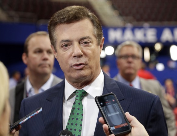 FILE - In this July 17, 2016 file photo, Trump Campaign Chairman Paul Manafort talks to reporters on the floor of the Republican National Convention at Quicken Loans Arena in Cleveland as Rick Gates l ...