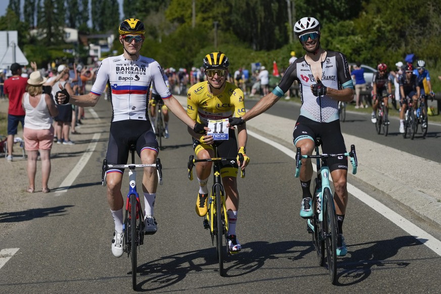 Three Slovenian riders Matej Mohoric, left, Slovenia&#039;s Tadej Pogacar, wearing the overall leader&#039;s yellow jersey, and Luka Mezgec, right, hold the race number of Pogacar&#039;s main rival an ...