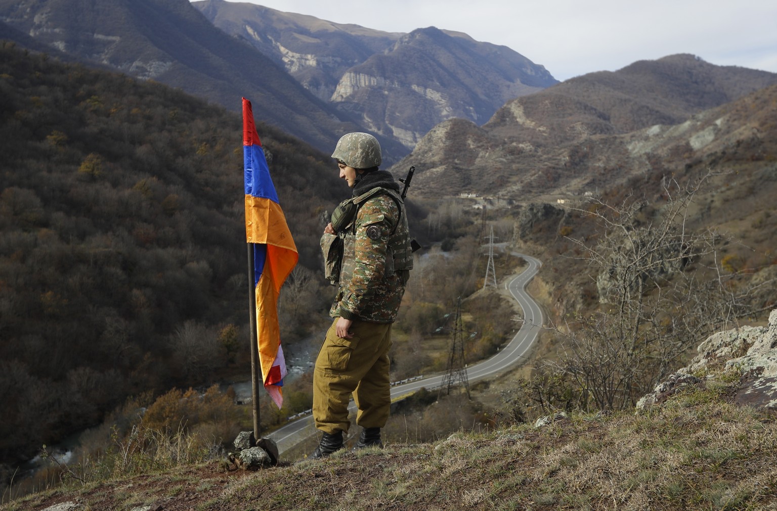 FILE - In this Wednesday, Nov. 25, 2020 file photo, an ethnic Armenian soldier stands guard next to Nagorno-Karabakh&#039;s flag atop of the hill near Charektar in the separatist region of Nagorno-Kar ...