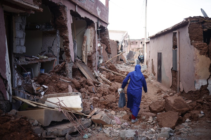 epaselect epa10853311 A woman passes by damaged buildings following a powerful earthquake in Ouirgane, south of Marrakesh, Morocco, 10 September 2023. A magnitude 6.8 earthquake that struck central Mo ...