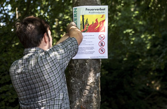 Revierfoerster Christoph Hitz befestigt ein Schild mit der Aufschrift "Feuerverbot Waldbrandgefahr" im Wald von Greppen am Donnerstag, 26. Juli 2018. Wegen der anhaltenden Trockenheit haben  ...