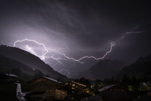 Ein verzweigter Blitz durchschneidet den Gewitterhimmel ueber dem Tal in Richtung Gsteig, aufgenommen von Gstaad (BE), Schweiz, am Donnerstag, 16. Juli 2026. Waehrend eine Hitzewelle weiterhin Teile d ...
