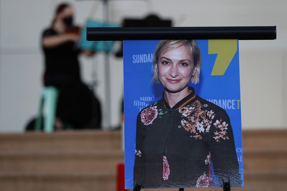 FILE - A musician plays a violin behind a photograph of cinematographer Halyna Hutchins during a vigil in her honor in Albuquerque, N.M., Oct. 23, 2021. Production is expected to resume this spring on ...