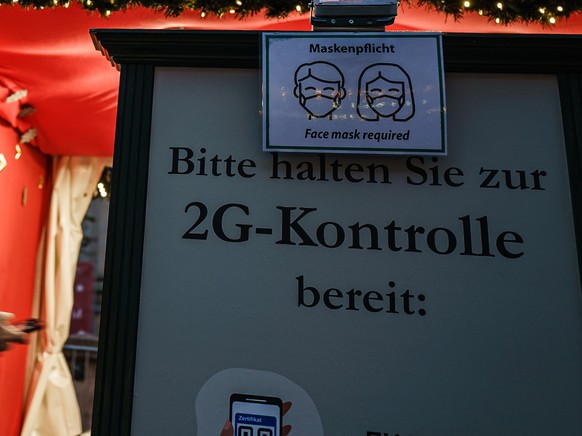 epa09611361 A note at the entrance of the Berlin Christmas market at Gendarmenmarkt square mentions the requirement of the so called ?2G rule? in Berlin, Germany, 29 November 2021. The 2G regulation r ...