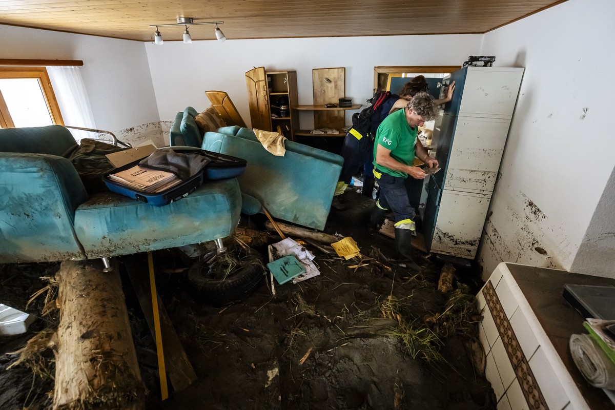 Elio Biadici, right, and his daughter Irina Biadici save photographs of the childhood of the children in the rubble-filled living room as they returned to her house for the first time after the storm  ...