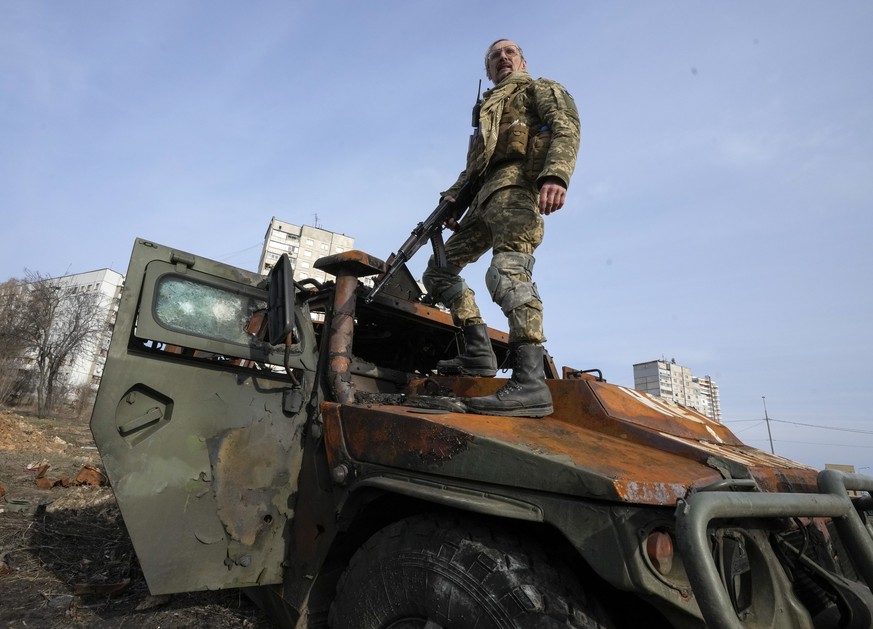A Ukrainian soldier stands a top a destroyed Russian APC after recent battle in Kharkiv, Ukraine, Saturday, March 26, 2022. With Russia continuing to strike and encircle urban populations, from Cherni ...