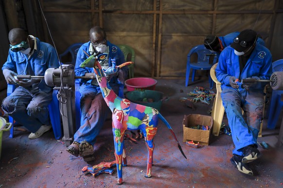 epa10228973 Kenyan workers from the social enterprise &#039;Ocean sole&#039; glue together old flip-flops as preparation for assembling them to art pieces at their workshop in Nairobi, Kenya, 06 Octob ...