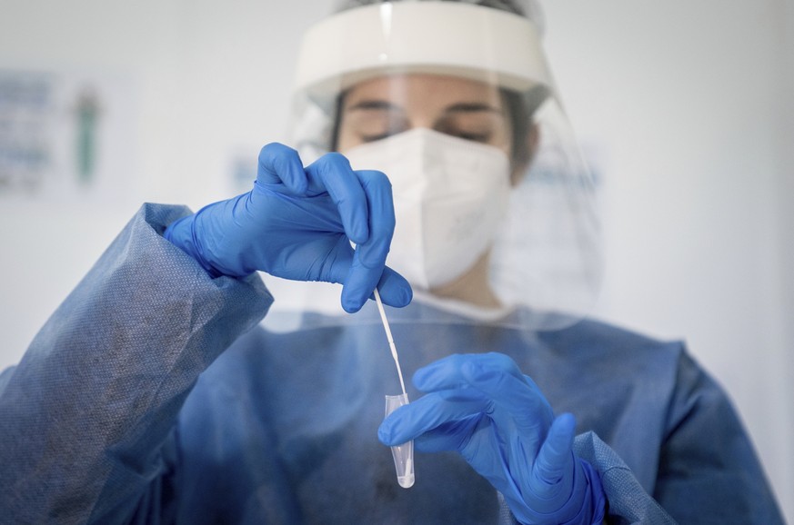 Medically trained personnel place the cotton swab in a solution for a Corona rapid test after the swab has been taken in Berlin, Germany, Thursday, Feb. 18, 2021. (Kay Nietfeld/dpa via AP)