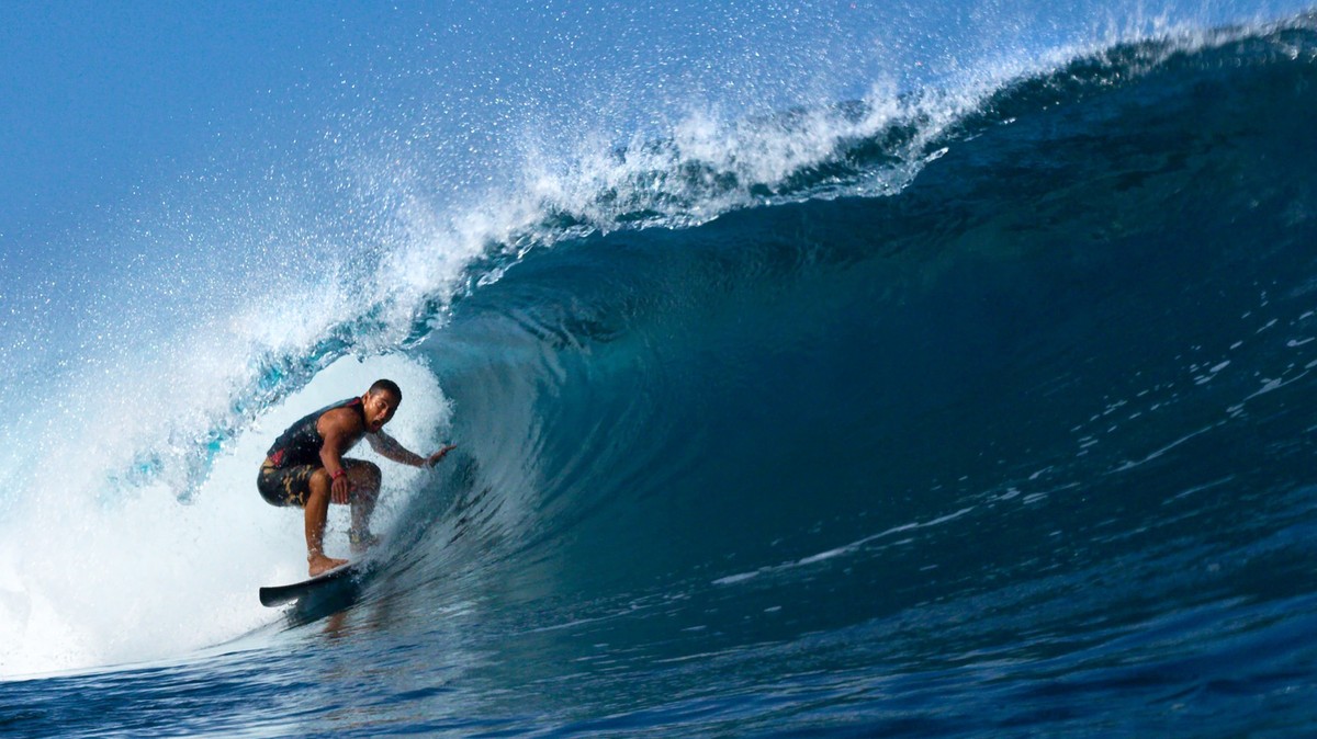 Tamayo Perry Surfing the Tube at Pipeline, Hawaii, Pro surfer, Tamayo Perry, rides a blue,tubing, wave while surfing at Pipeline on the North Shore of Oahu, Hawaii.