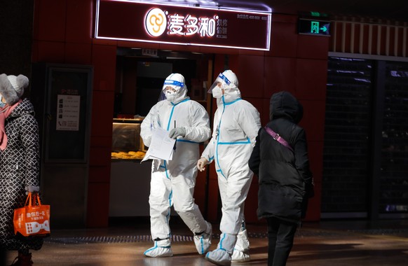 epa10366636 Health volunteer workers wearing protective suit walk at the Beijing West Railway Station in Beijing, China, December 15, 2022. According to the notification of the Beijing Municipal Bureau of…