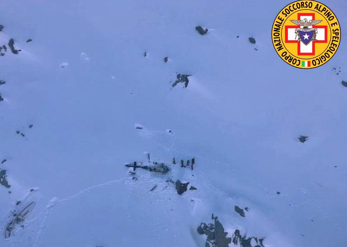 Rescuers stand next to the debris of an helicopter after a midair collision between a small tourist airplane and a helicopter carrying skiers to a glacier in the northwestern region of Val d'Aost ...
