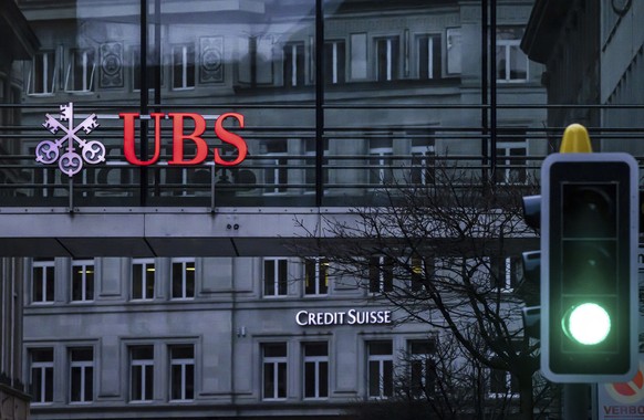 FILE - A traffic light signals green in front of the logos of the Swiss banks Credit Suisse and UBS in Zurich, Switzerland, March 19, 2023. UBS says it has completed its takeover of embattled rival Cr ...