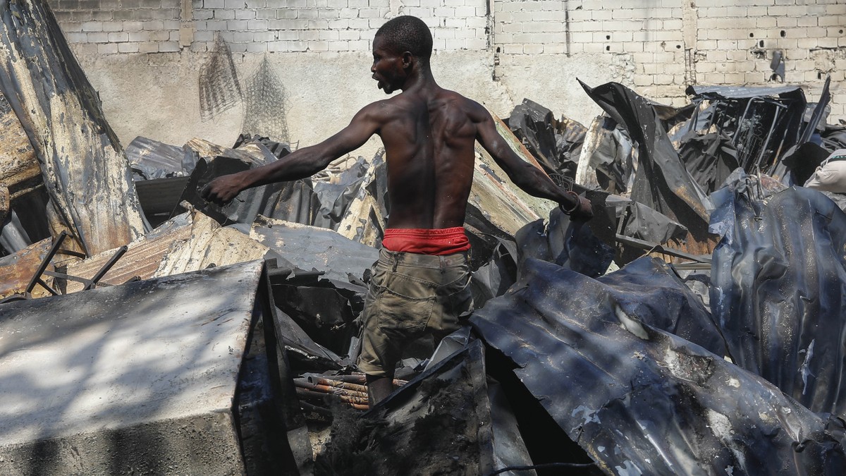 A man looks for salvageable items at a car mechanic shop that was set fire during gang violence in Port-au-Prince, Haiti, Monday, March 25, 2024. (AP Photo/Odelyn Joseph)