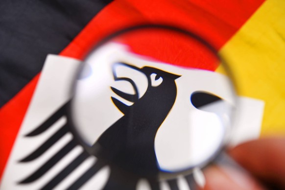 Lupe ¸ber der Fahne von Deutschland und dem deutschen Bundesadler, Symbolfoto f¸r Spionage in Deutschland nur redaktionelle Nutzung *** Magnifying glass over the flag of Germany and the German federal ...