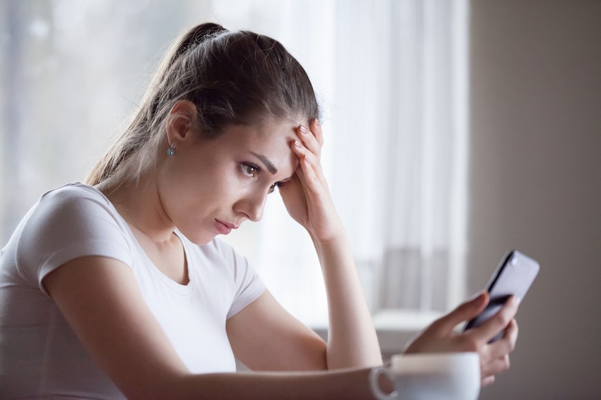 Angry young woman looking at smartphone frustrated by no signal or scam message, mad female disappointed by bad news reading on phone, upset girl get negative or rejection response on mobile