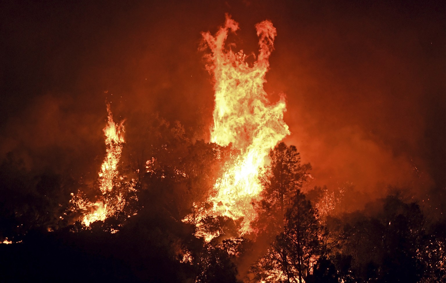 High winds cause tree canopies to flare up as a wildfire burns east of Midpines in Mariposa County, Calif., Friday, July 22, 2022. The fast-moving wildfire near Yosemite National Park erupted Friday a ...