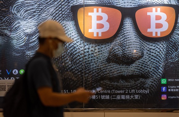 epaselect epa09486742 A man walks past an advertising poster for Bitcoins and cryptocurrencies in Hong Kong, China, 25 September 2021. On 24 September, China intensified the crackdown on cryptocurrenc ...