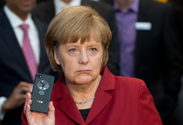 The March 5, 2013 photo shows German Chancellor Angela Merkel presenting a tap-proof mobile phone of Blackberry at a booth of Secusmart during the opening round tour of the world&#039;s largest comput ...